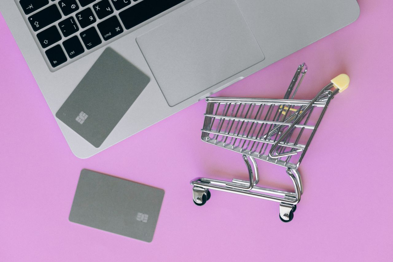 services-02 A minimalist flat lay of a credit card, laptop, and miniature shopping cart.